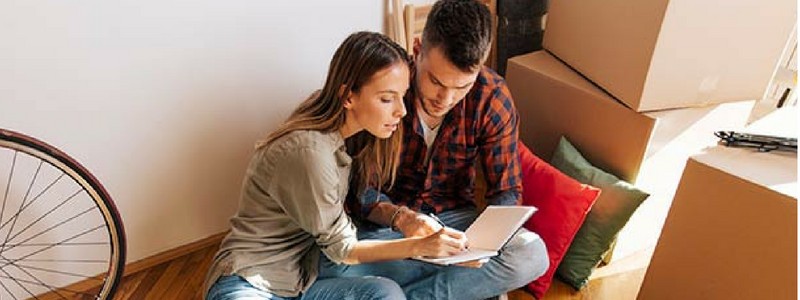 a couple is sitting on the floor and reading a book
