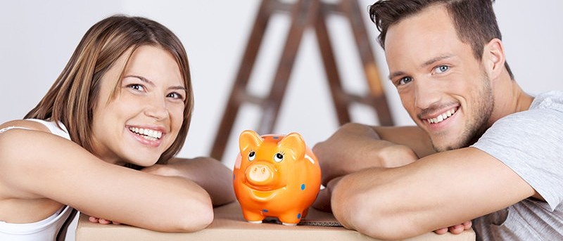 young couple posing for a picture with a piggy bank