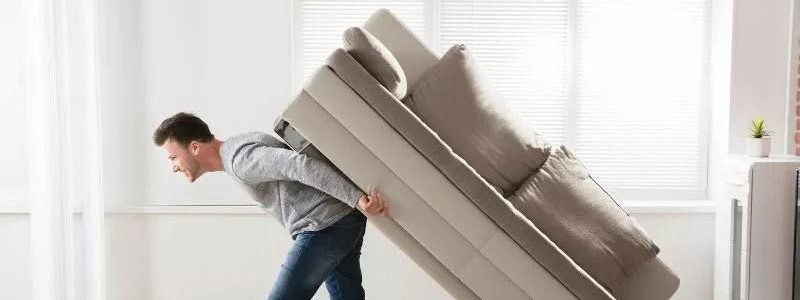 young man trying to move a couch alone