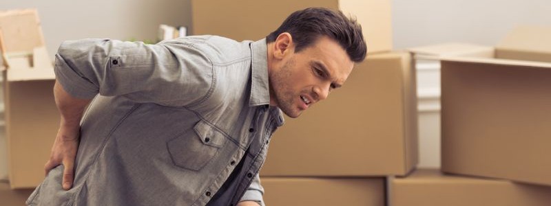 young man feeling back pain during a household relocation
