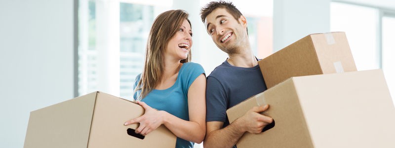 young couple holding cardboard boxes preparing for a household relocation