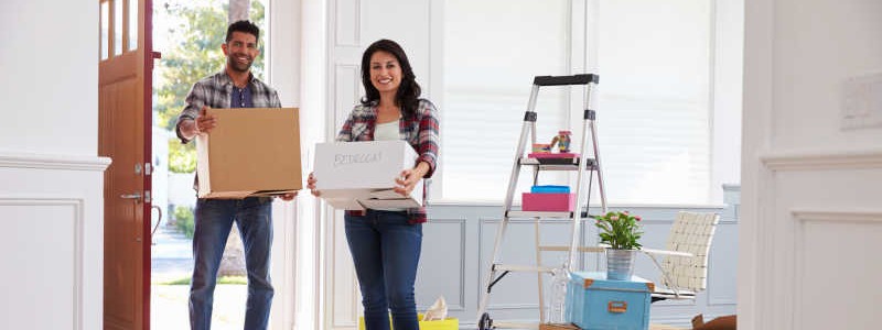 young couple with cardboard boxes standing inside of their new house