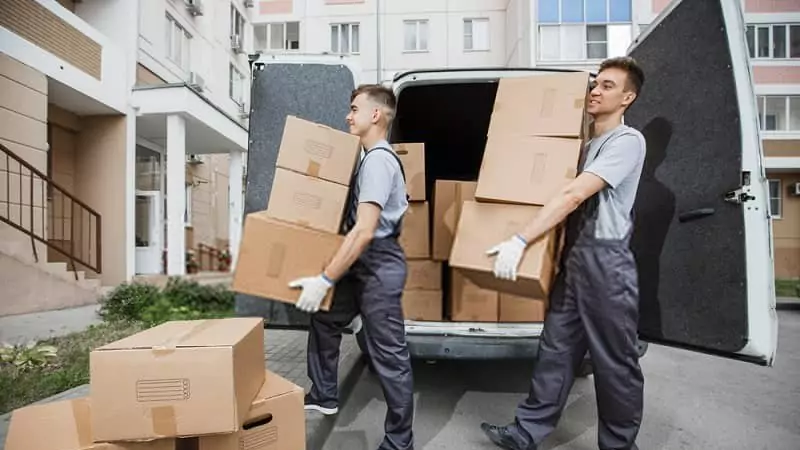 young professionals holding cardboard boxes in hands unloading a truck