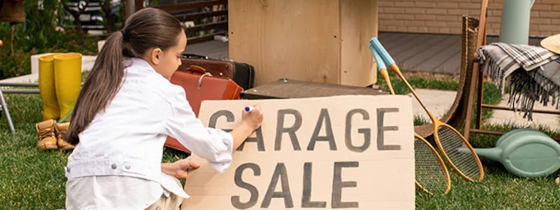 Young girl writing garage sale on a board