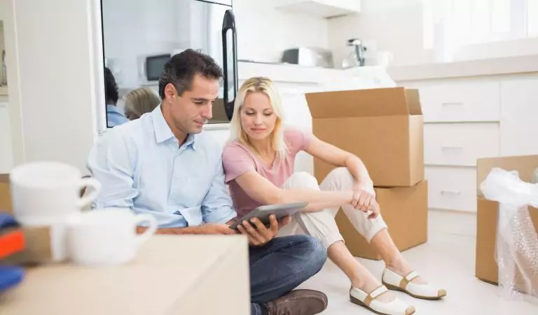 couple sitting on the floor and checking something on a tablet