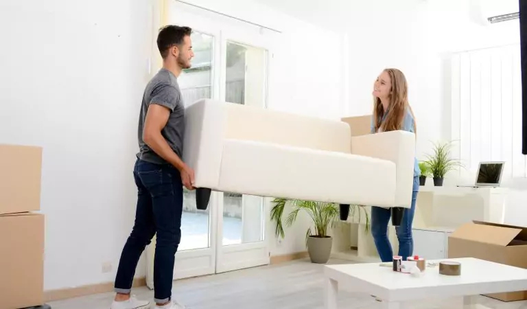 couple lifting a heavy couch and preparing to relocate it