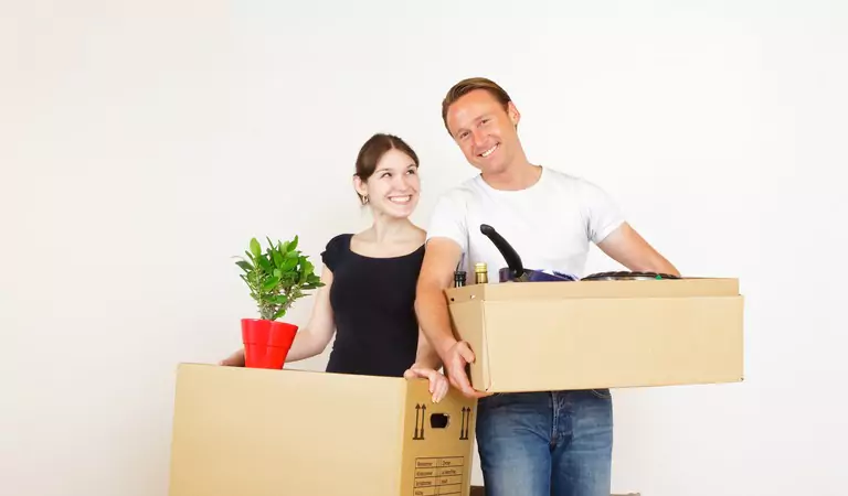 couple inside of a house with cardboard boxes and a plant