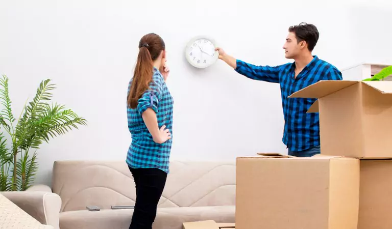 man removing a clock from a wall and a woman looking at him