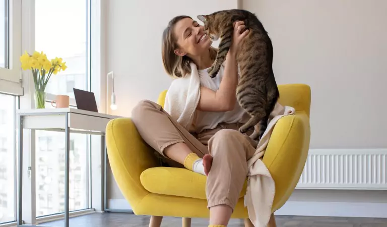 woman sitting on a chair with and playing with her cat
