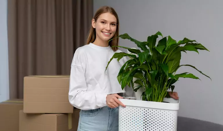 Woman holding a houseplant inside of a house