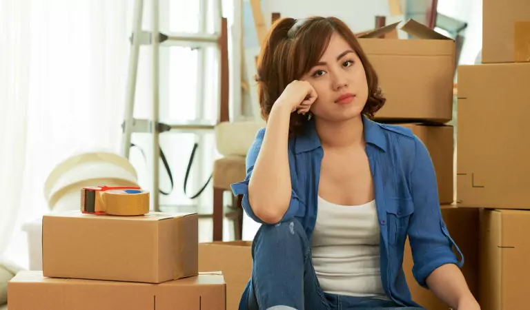 young woman looking worried and some cardboard boxes at the back