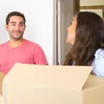 couple with some cardboard boxes inside of a house