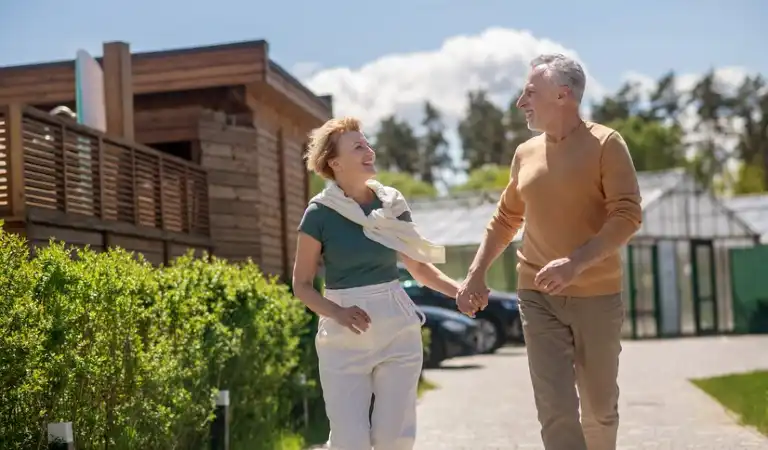 Old couple holding their hands walking on a road