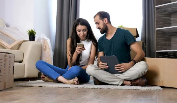 Beautiful young couple just moving in new flat and they are sitting on the floor