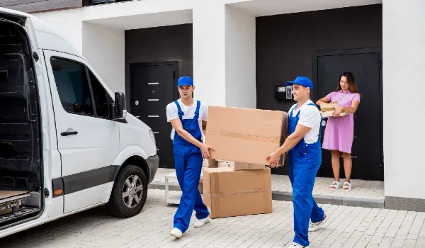 Two removal company workers are loading boxes into a minibus